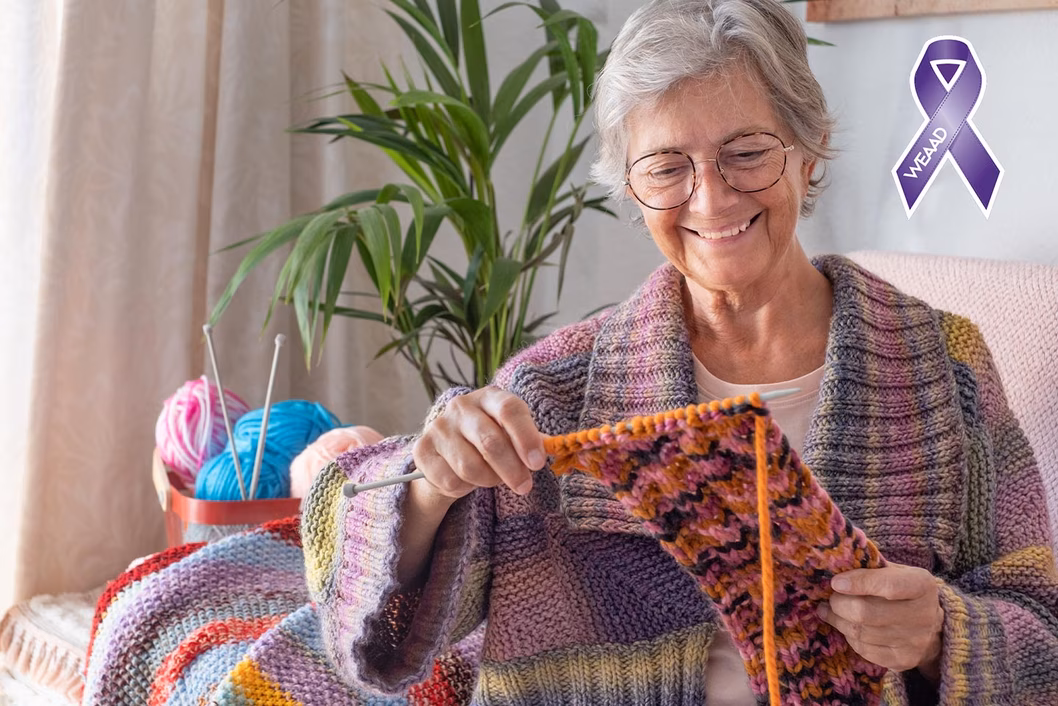 Photo of a woman smiling at her knitting