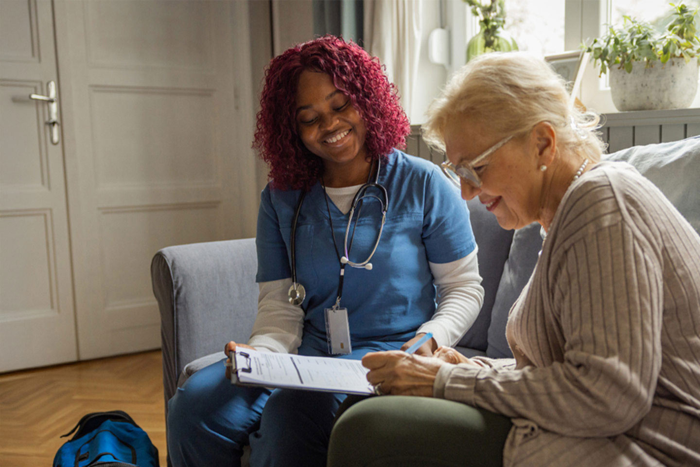 Photo of a health worker sitting with a woman filling out a form
