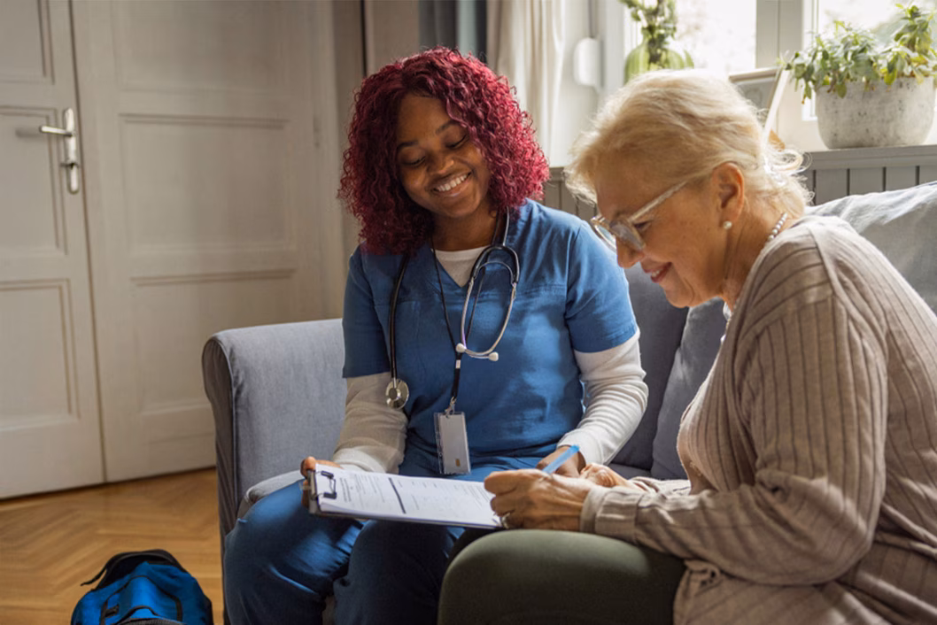Photo of a health worker sitting with a woman filling out a form