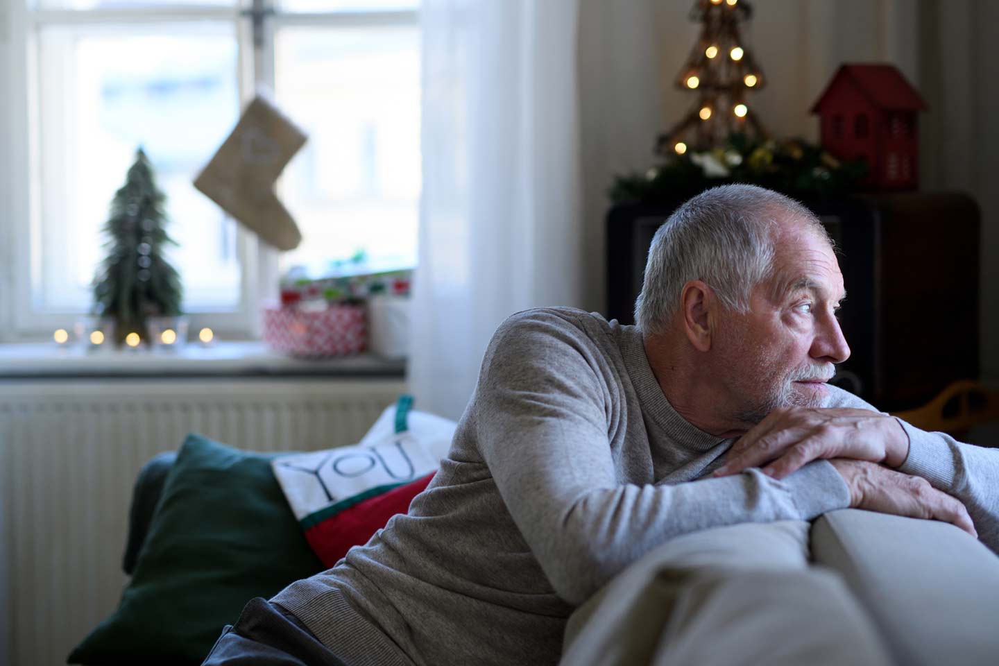 Photo of a man looking wistfully outside from the back of a sofa