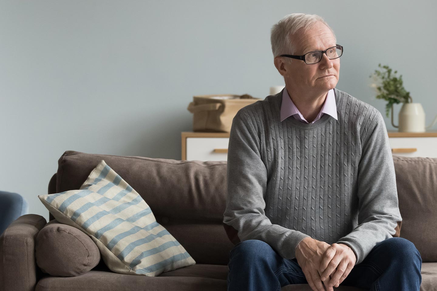 Photo of a pensive man sitting on a comfortable sofa