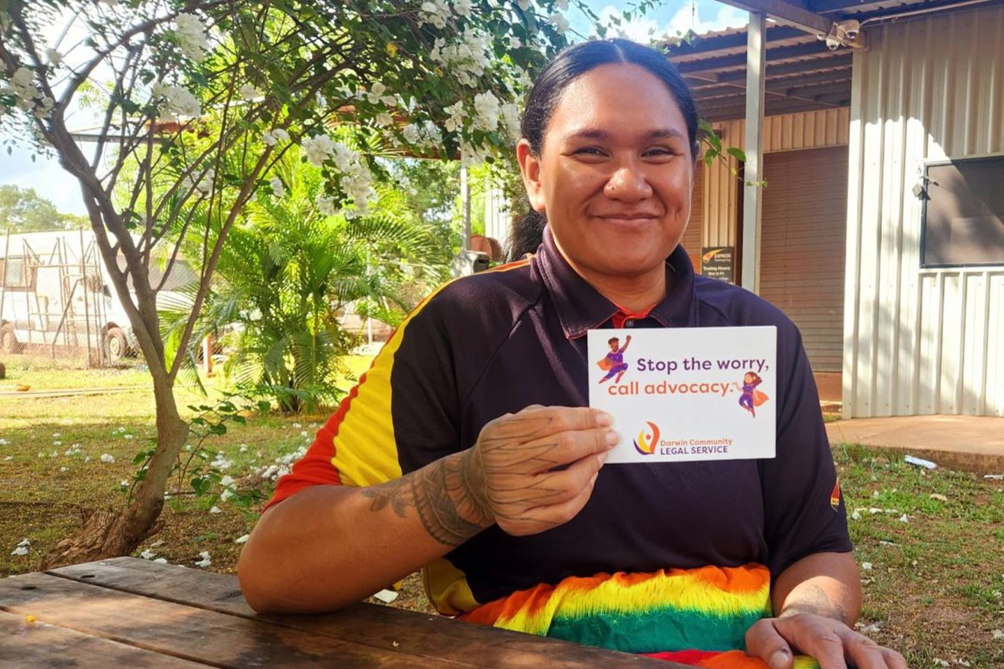 Photo of a woman sitting at a table under a tree