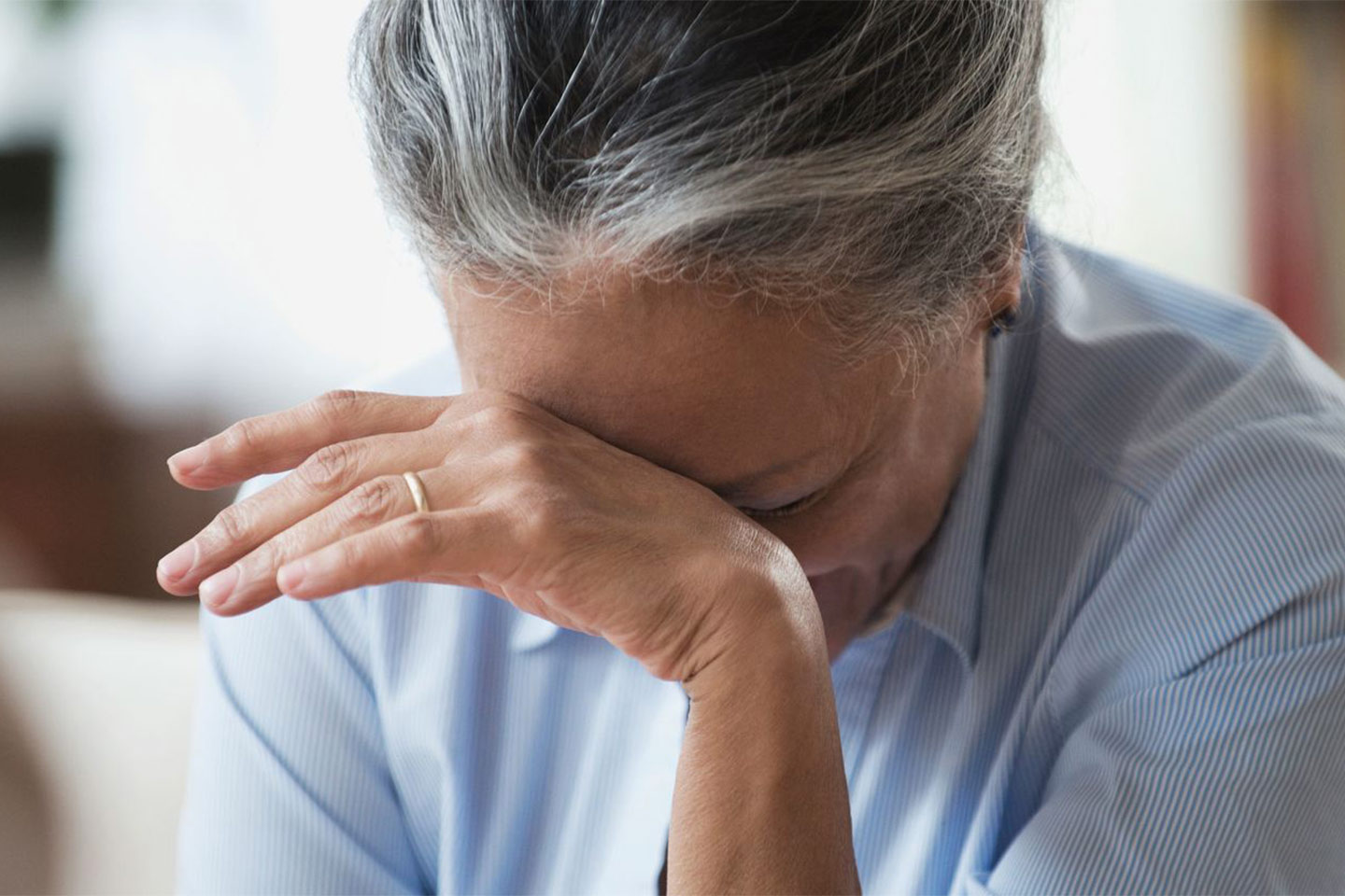 Photo of a woman resting her forehead on the back of her hand