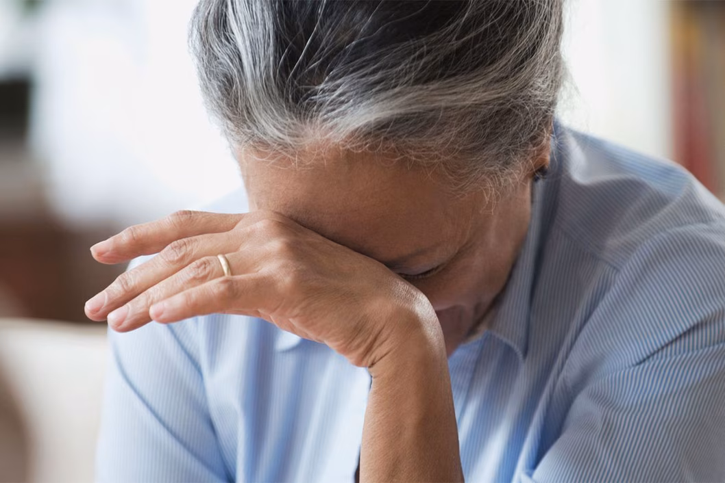 Photo of a woman resting her forehead on the back of her hand