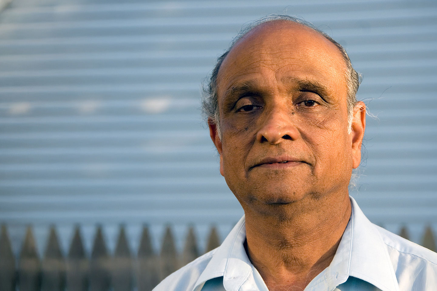 Photo of a man standing in front of a picket fence