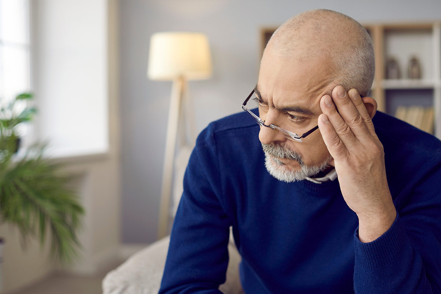Photo of a man in a grey room resting his head on his fingertips