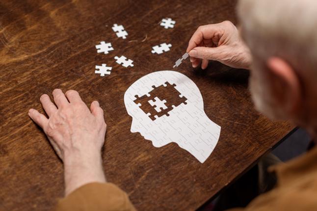 Photo of a man doing a jigsaw puzzle of a human head