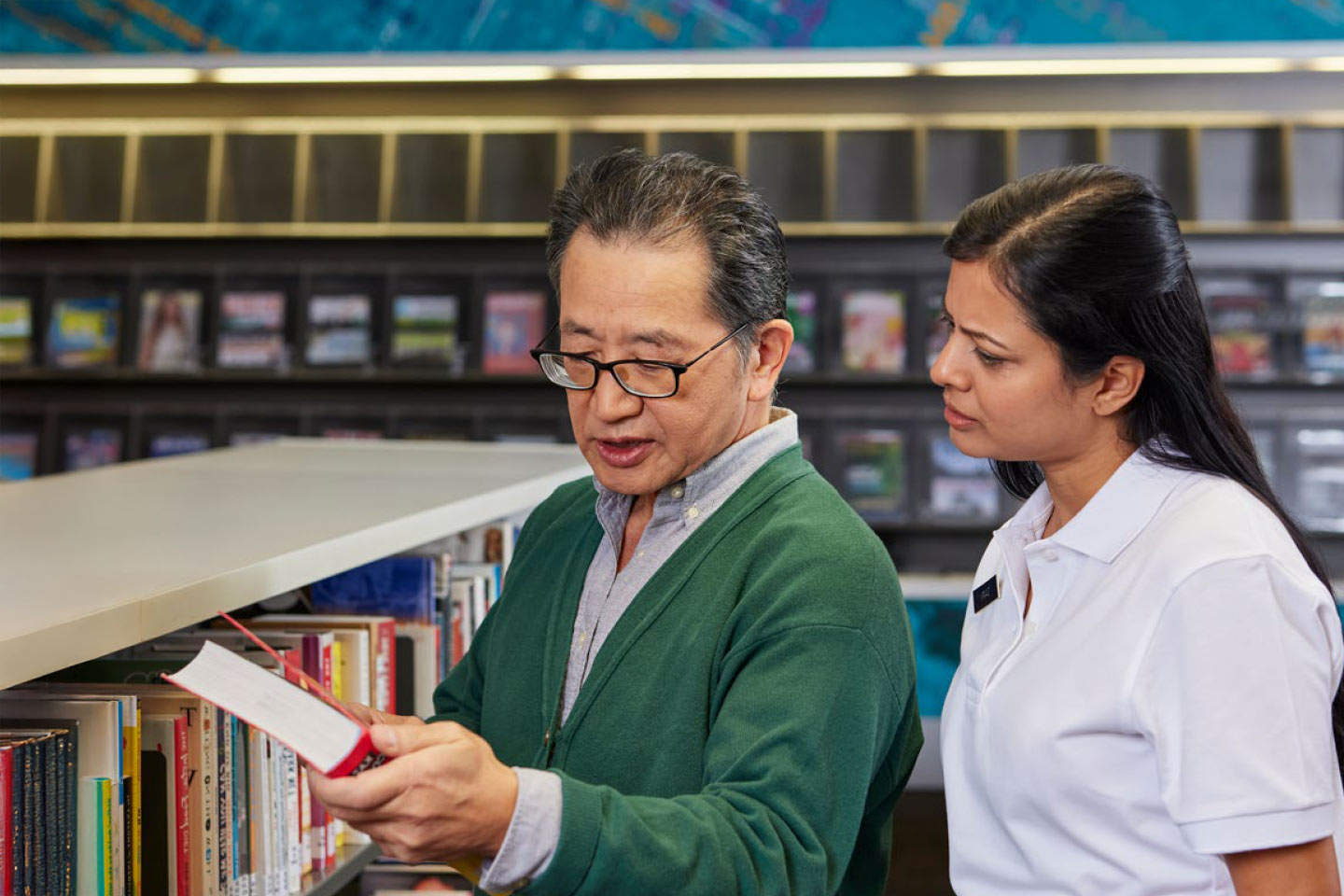 Photo of two people looking at books in a library