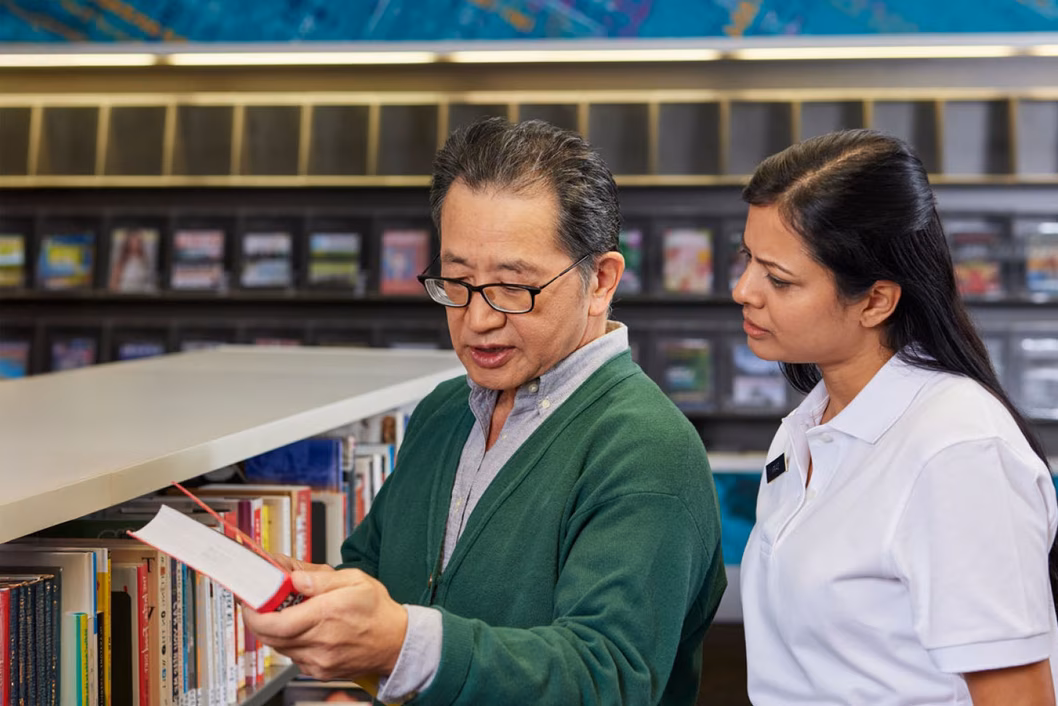 Photo of two people looking at books in a library