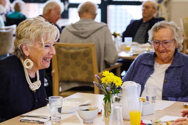 Photo of Maggie Beer seated in an aged care dining room