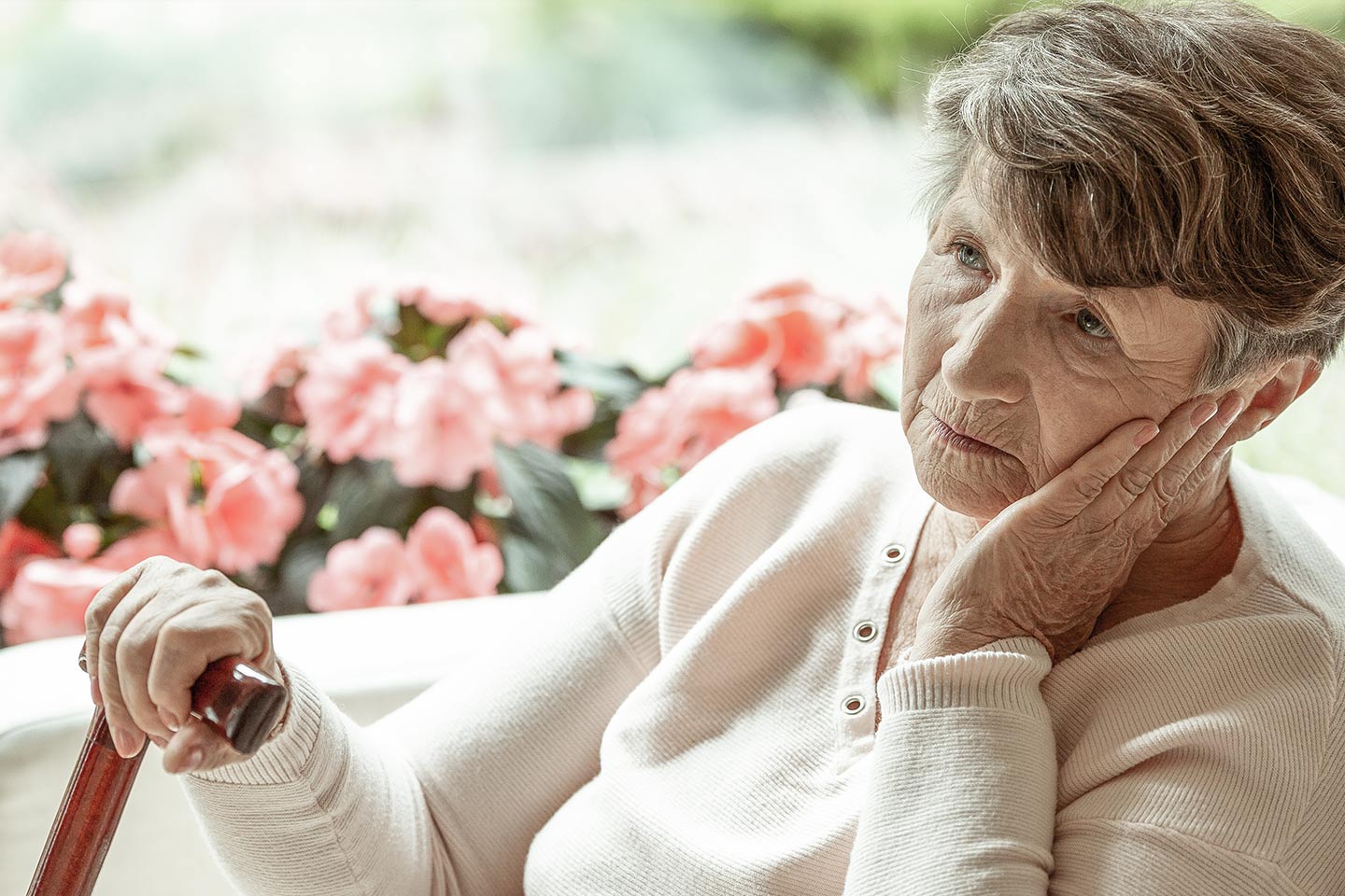 Photo of a woman with a walking stick sitting in front of flowers