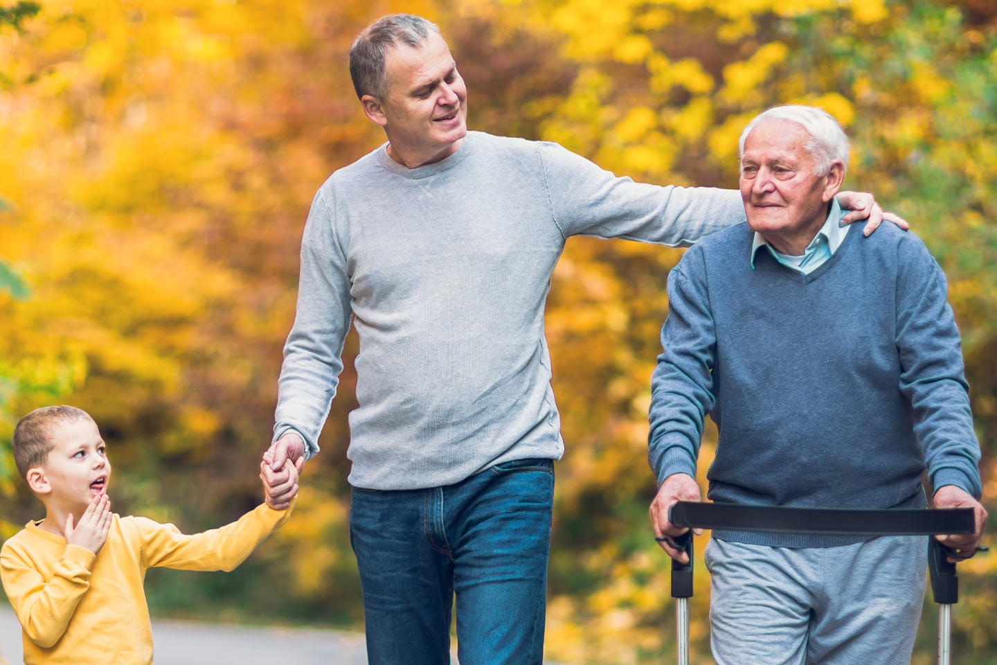 Photo of young boy, middle aged man, and senior man in an autumn park