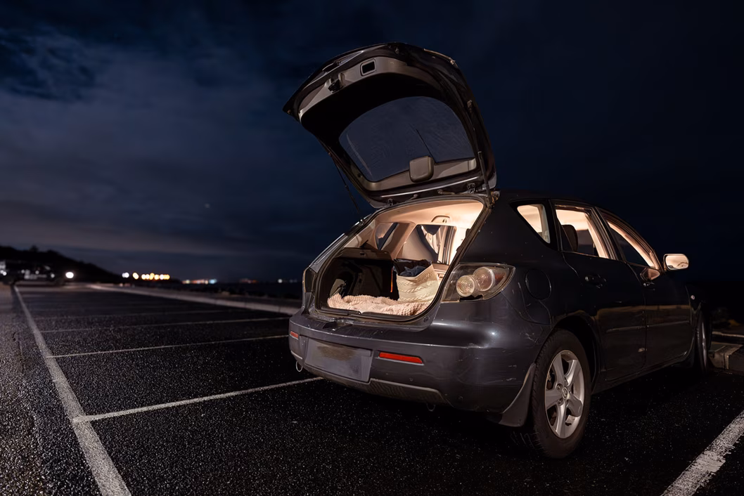 Photo of a car at night with a bed visible through the open rear hatch