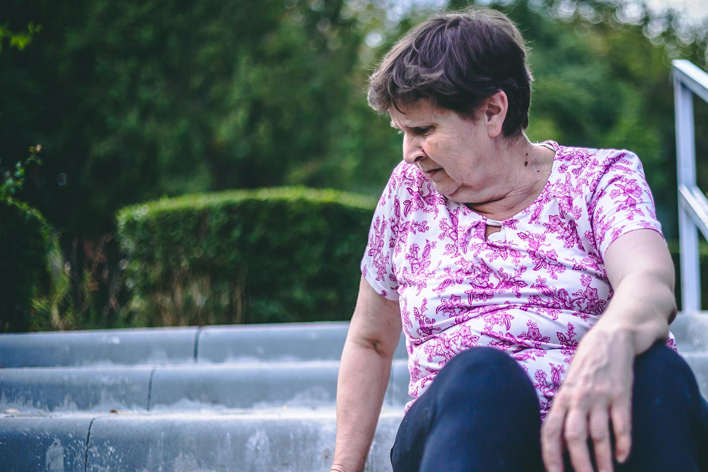 Photo of a woman in a floral pink t-shirt sitting outside