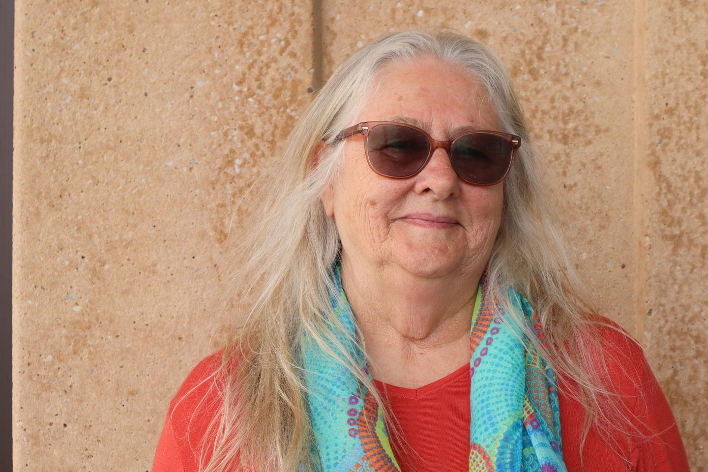 Photo of woman in a red top and blue scarf wearing sun glasses