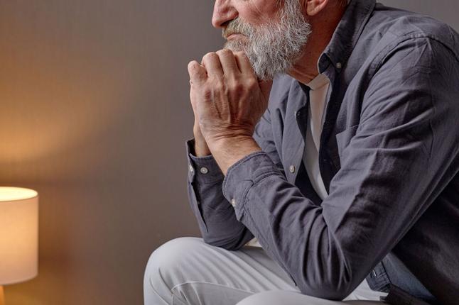 Senior man sitting with head in hands