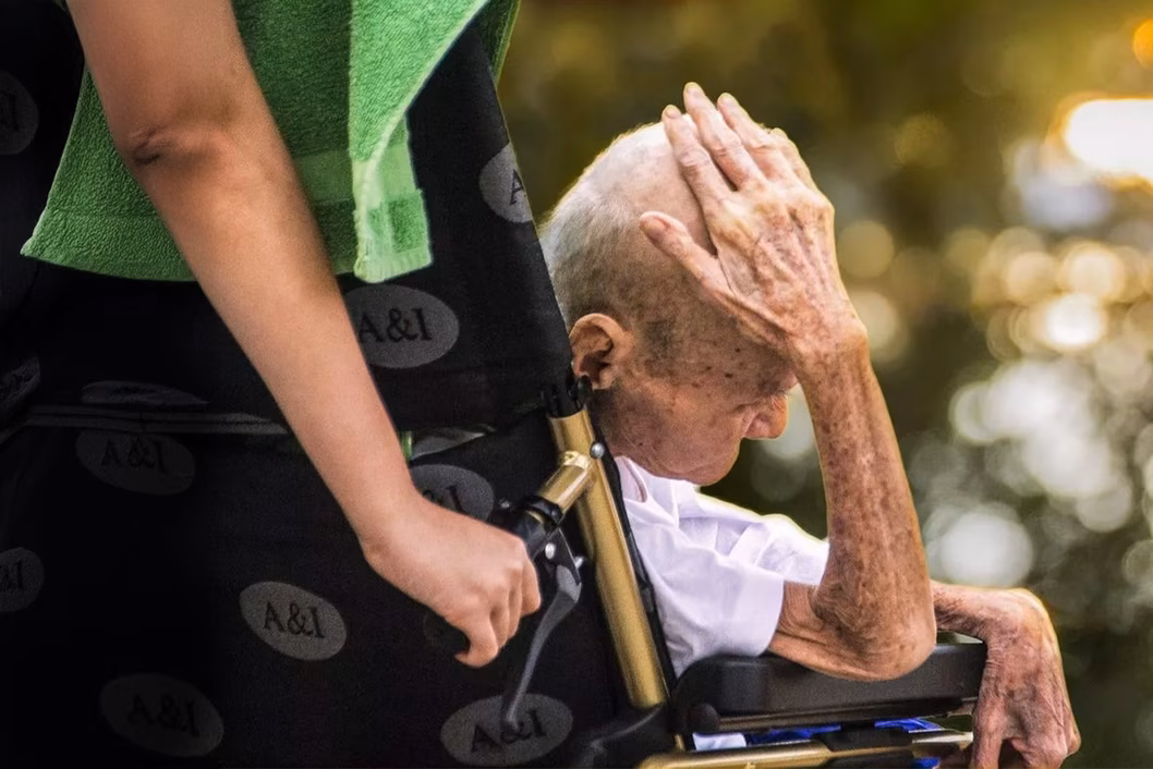 Photo of a very senior person being wheeled in a wheelchair