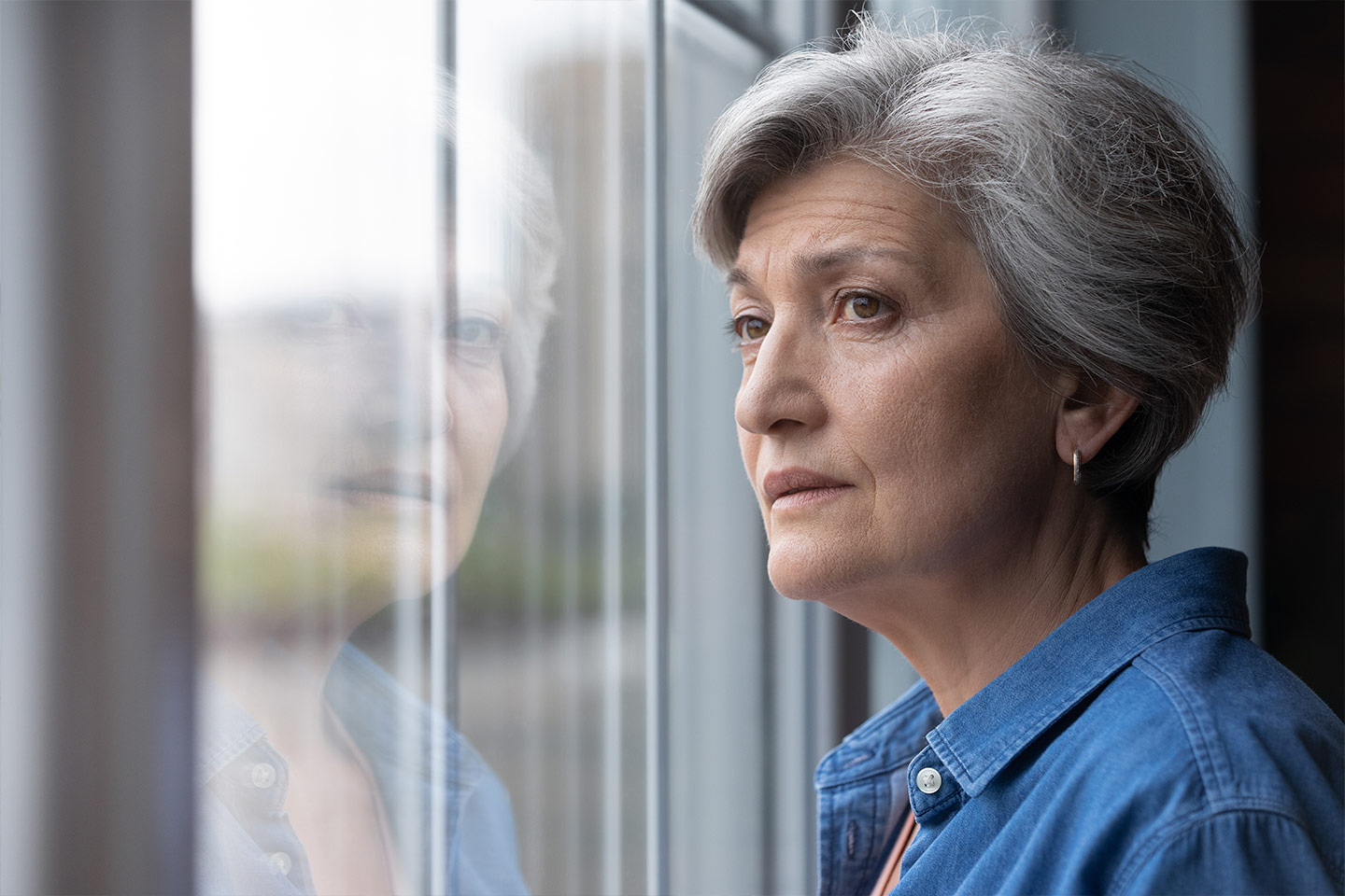 Photo of woman in a blue shirt looking out a window