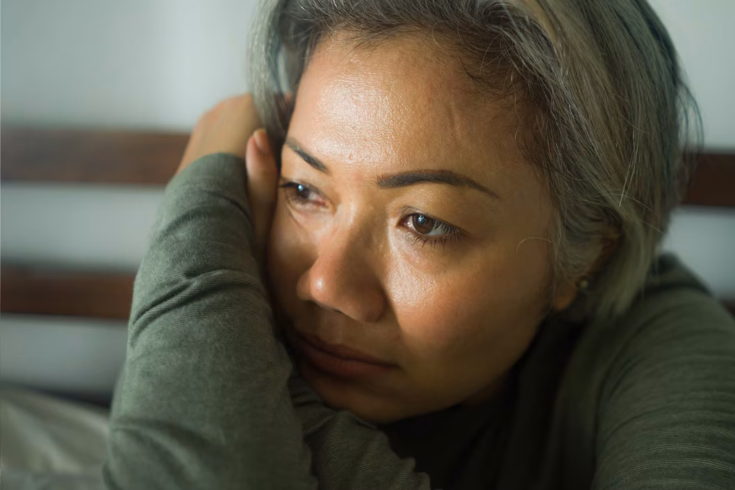 Photo of a sad woman in a sage green top