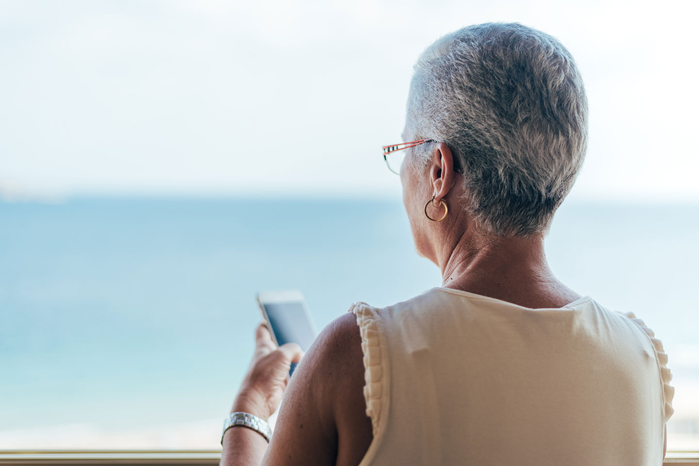Senior woman using her phone and looking out the window