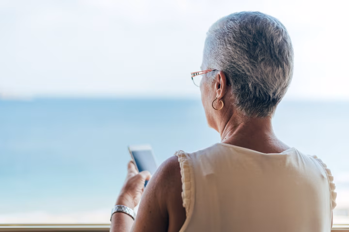 Senior woman using her phone and looking out the window
