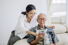 Người chăm sóc giúp người đàn ông cao tuổi sử dụng điện thoại di động