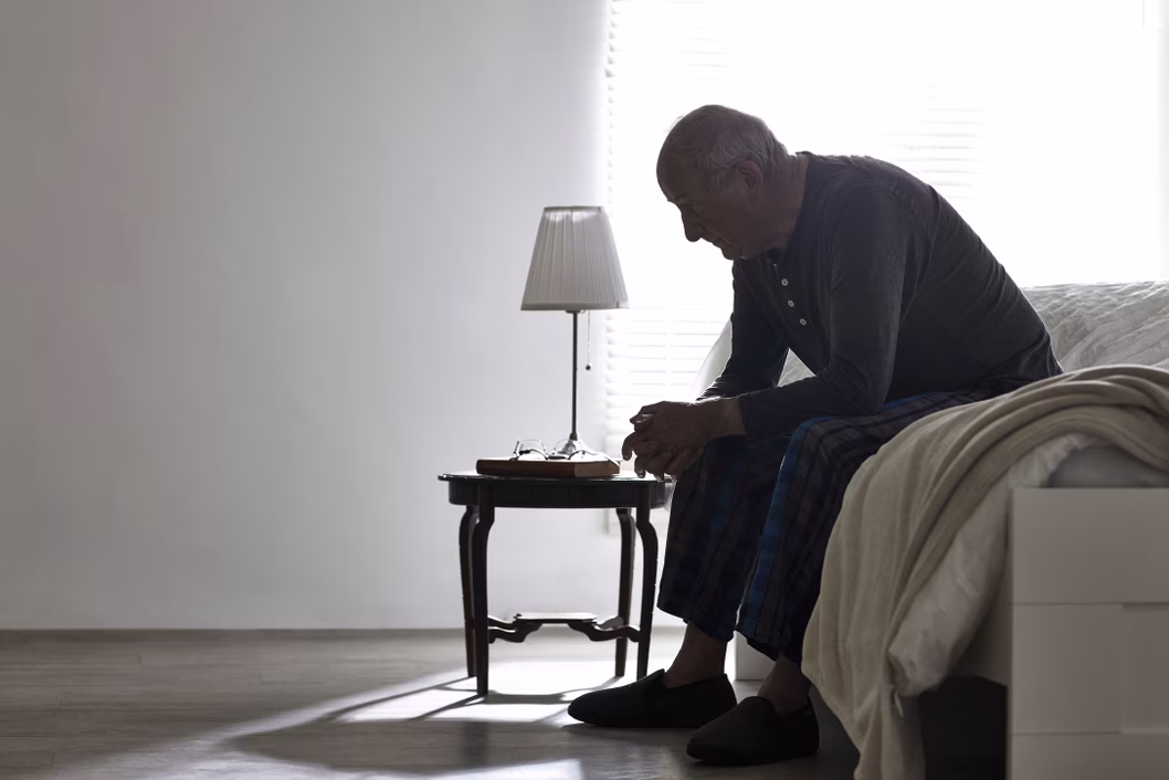 Senior man sitting at the end of the bed