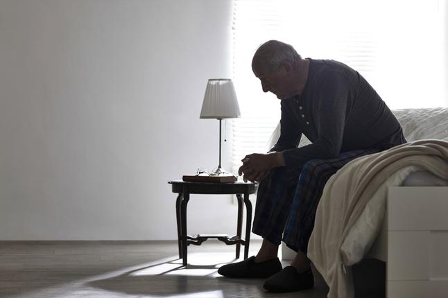Senior man sitting at the end of the bed