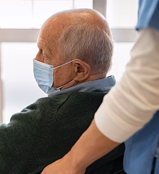 Photo of a man in a green jumper and blue surgical mask