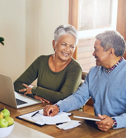 Photo of a couple smiling as they work on a laptop