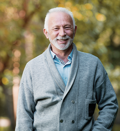 Photo of a smiling man in a cardigan outdoors