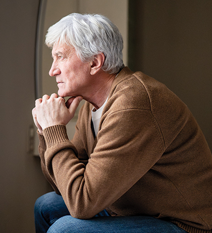 Photo of a man looking out a window with his chin on his hands