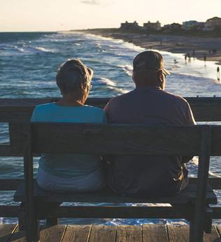 Photo of two people sitting on a bench overlooking a beach