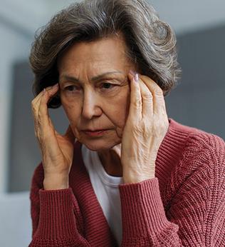 Photo of woman in a red cardigan rubbing her temples
