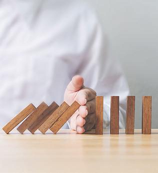Photo of a hand preventing a row of dominoes falling