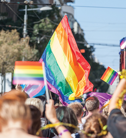 Photo of a Pride Parade with colourful flags raised