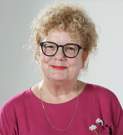 Photo of a smiling woman in a magenta shirt and black glasses