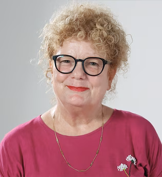 Photo of a smiling woman in a magenta shirt and black glasses