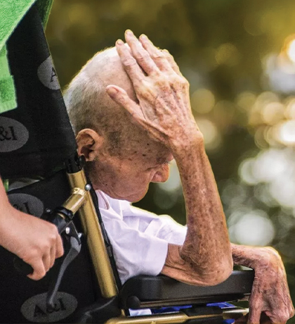 Photo of a very senior person being wheeled in a wheelchair