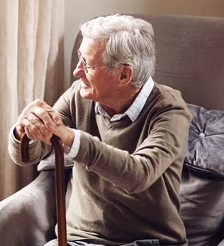 Photo of a man with a walking stick looking out a window