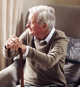 Photo of a man with a walking stick looking out a window