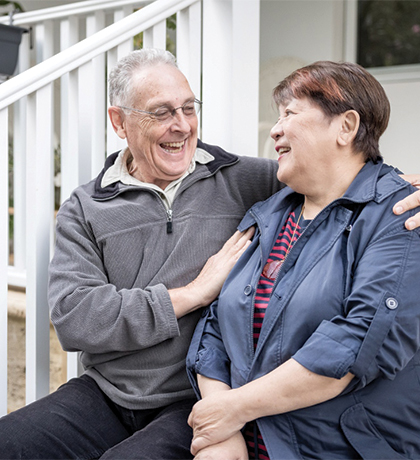 Photo of a couple sitting on a verandah and laughing together