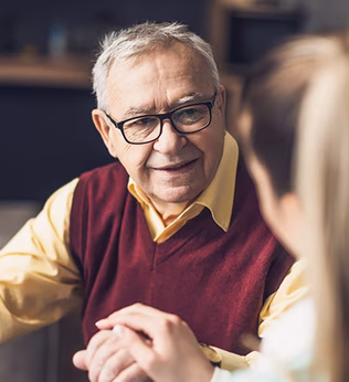 Photo of a man with a maroon vest and a yellow shirt