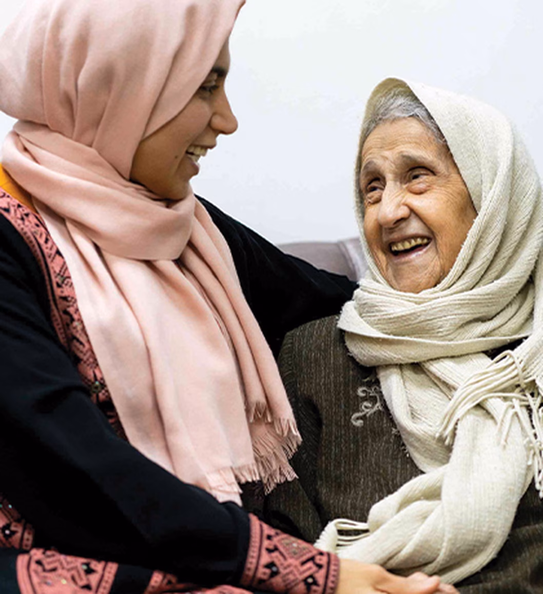 Photo of two women laughing and wearing headscarves