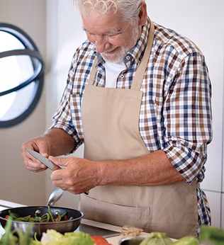 Photo of a man in an apron peeling veggies in a kitchen