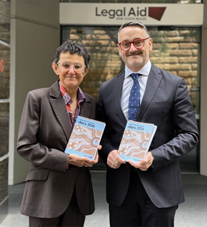 Photo of two people in suits holding books and smiling