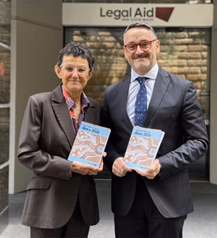 Photo of two people in suits holding books and smiling