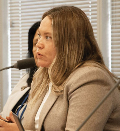 Photo of a woman in a jacket speaking into a microphone