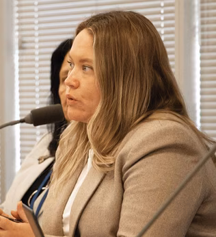 Photo of a woman in a jacket speaking into a microphone
