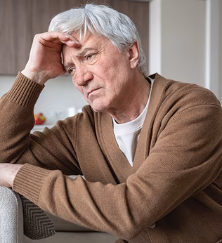 Photo of a despondent man resting his head on his hand